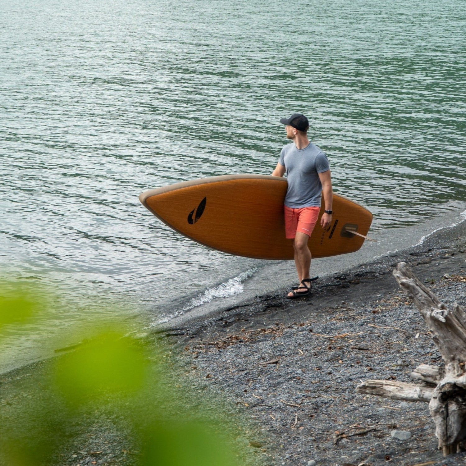 man holding inflatable paddle board isup along shoreline