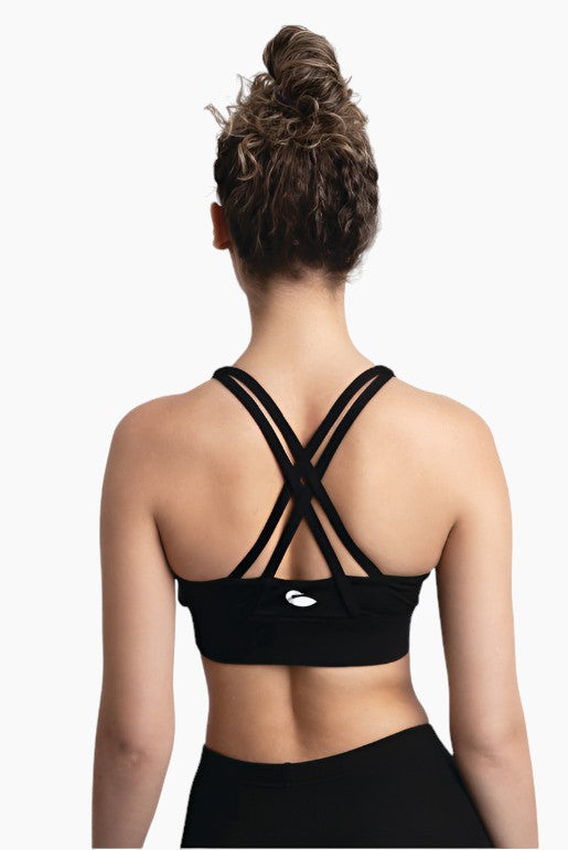 Woman wearing an athletic top with criss-crossed straps in the back.