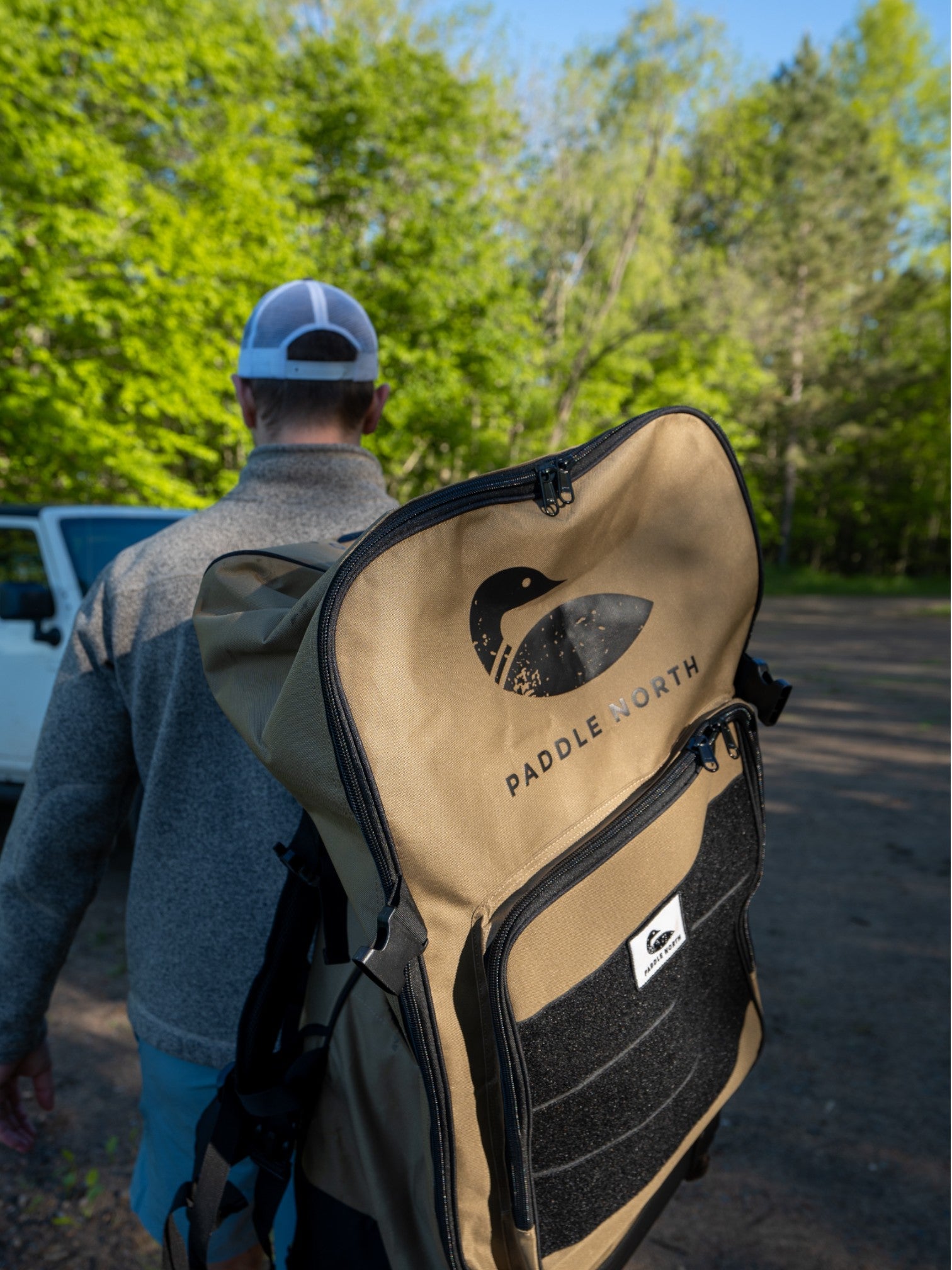 Person carrying a tan paddle north backpack with black accents outside.