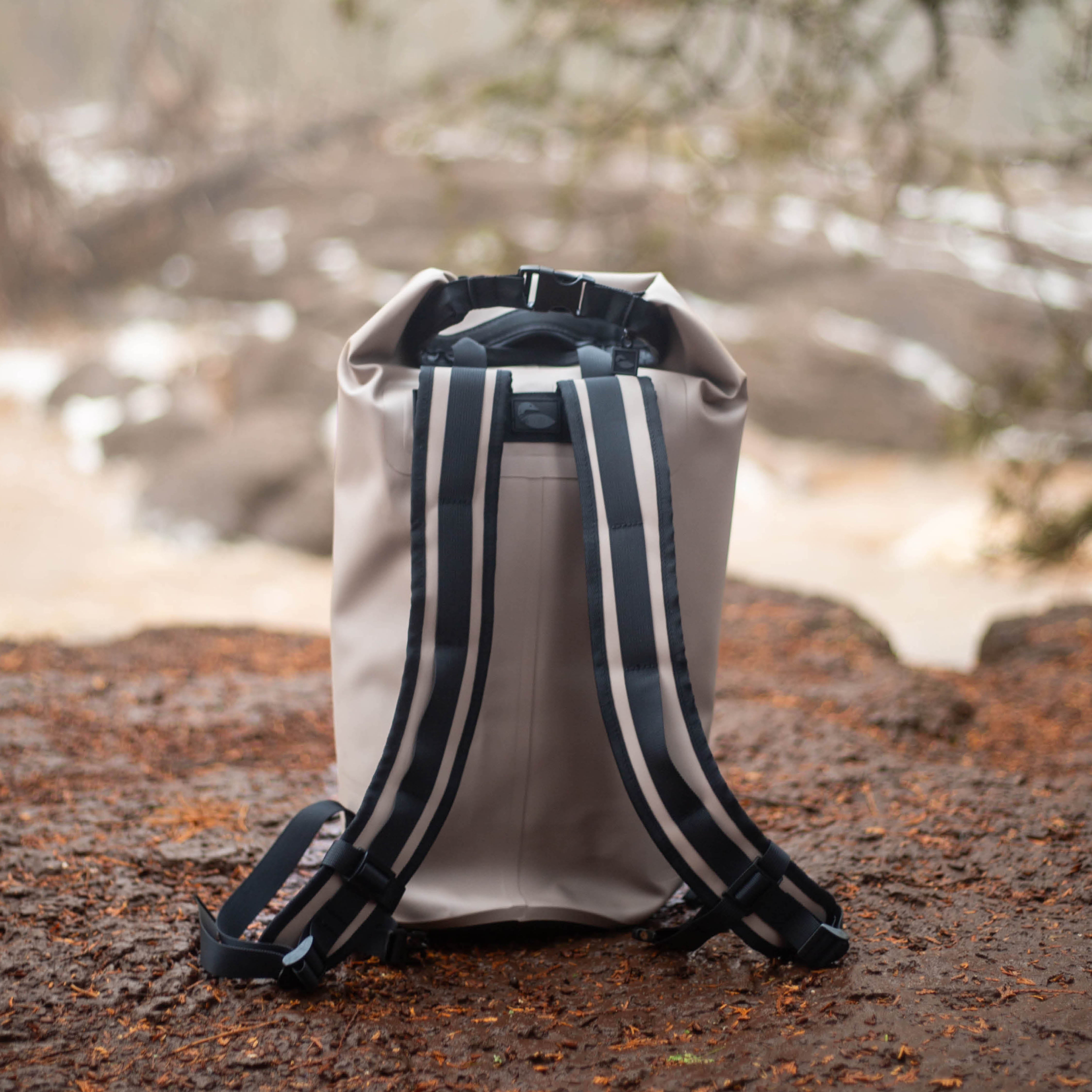 Waterproof dry cooler backpack sitting next to waterfall on a hiking trail