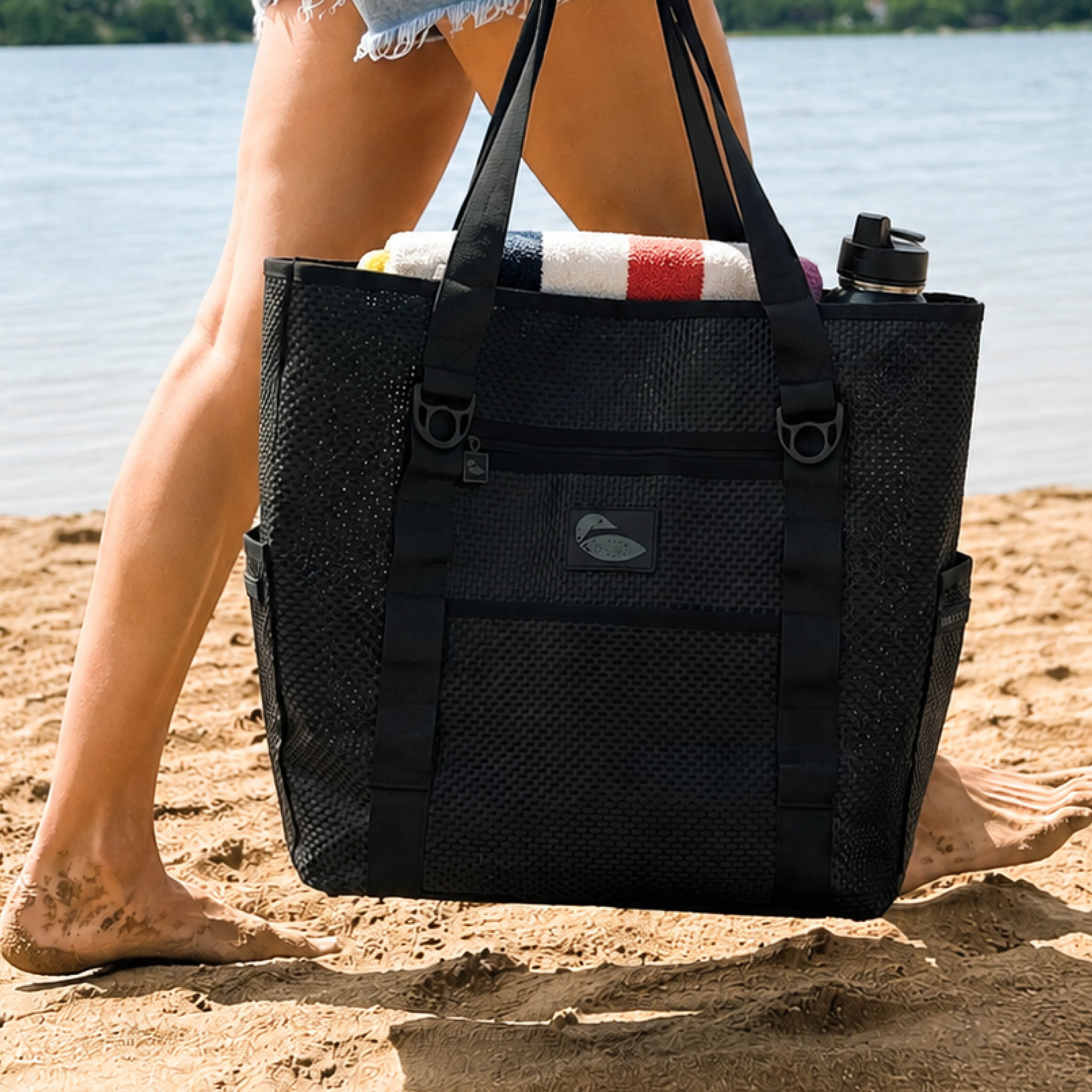 Black beach tote bag being carried across a sandy beach