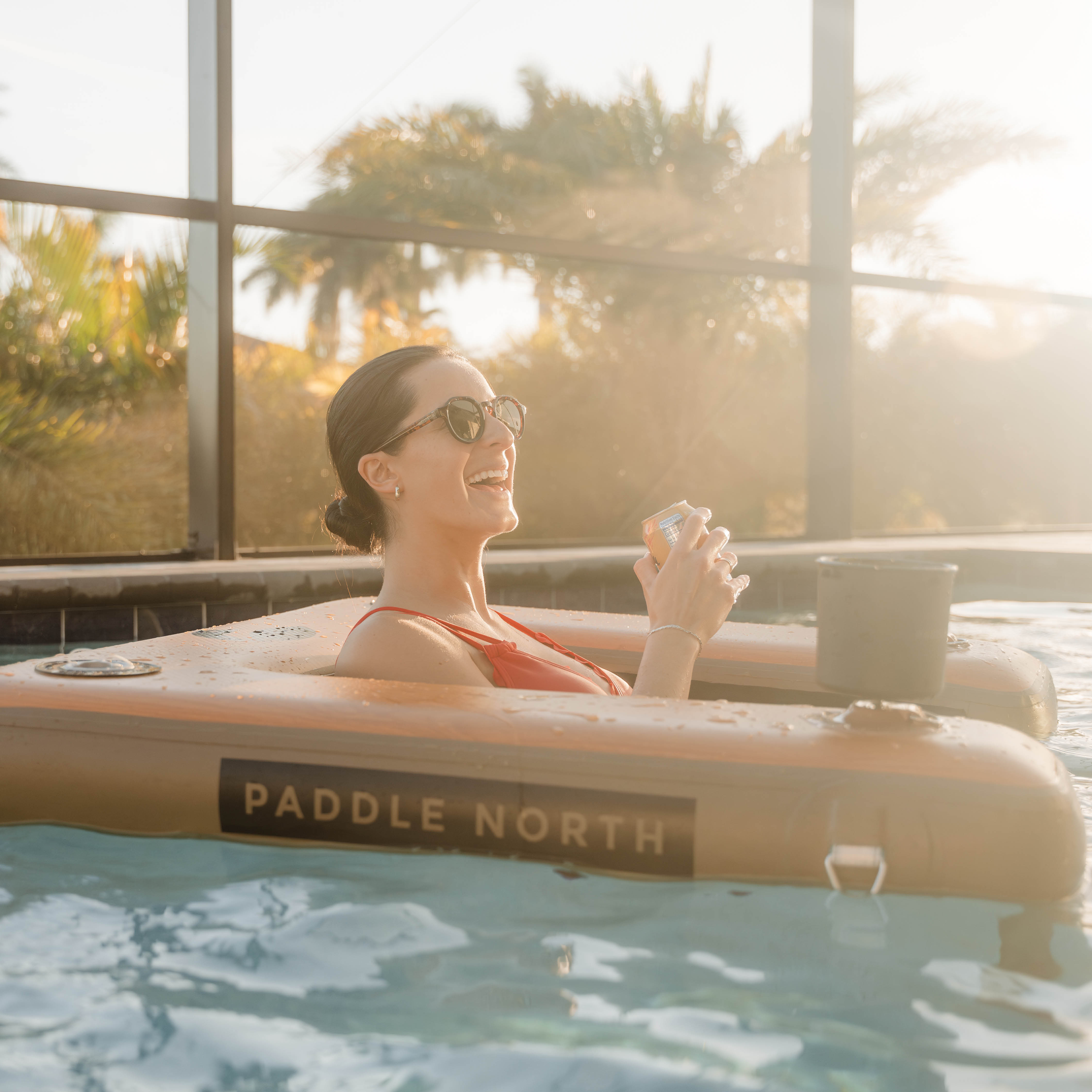 Woman relaxing in inflatable Floating Chair in pool with beautiful sunset