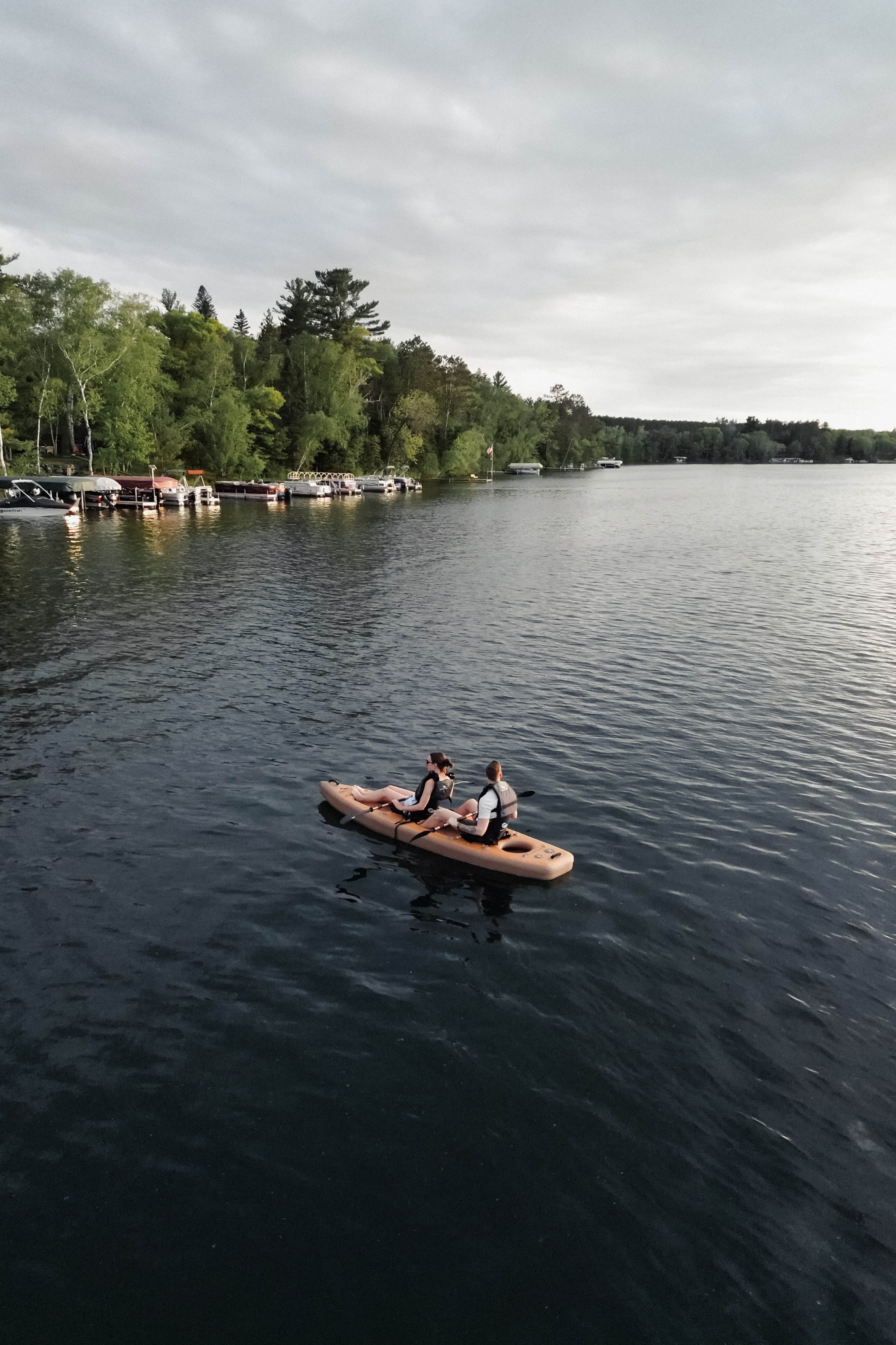 Couple paddling tandem inflatable kayak on a lake.