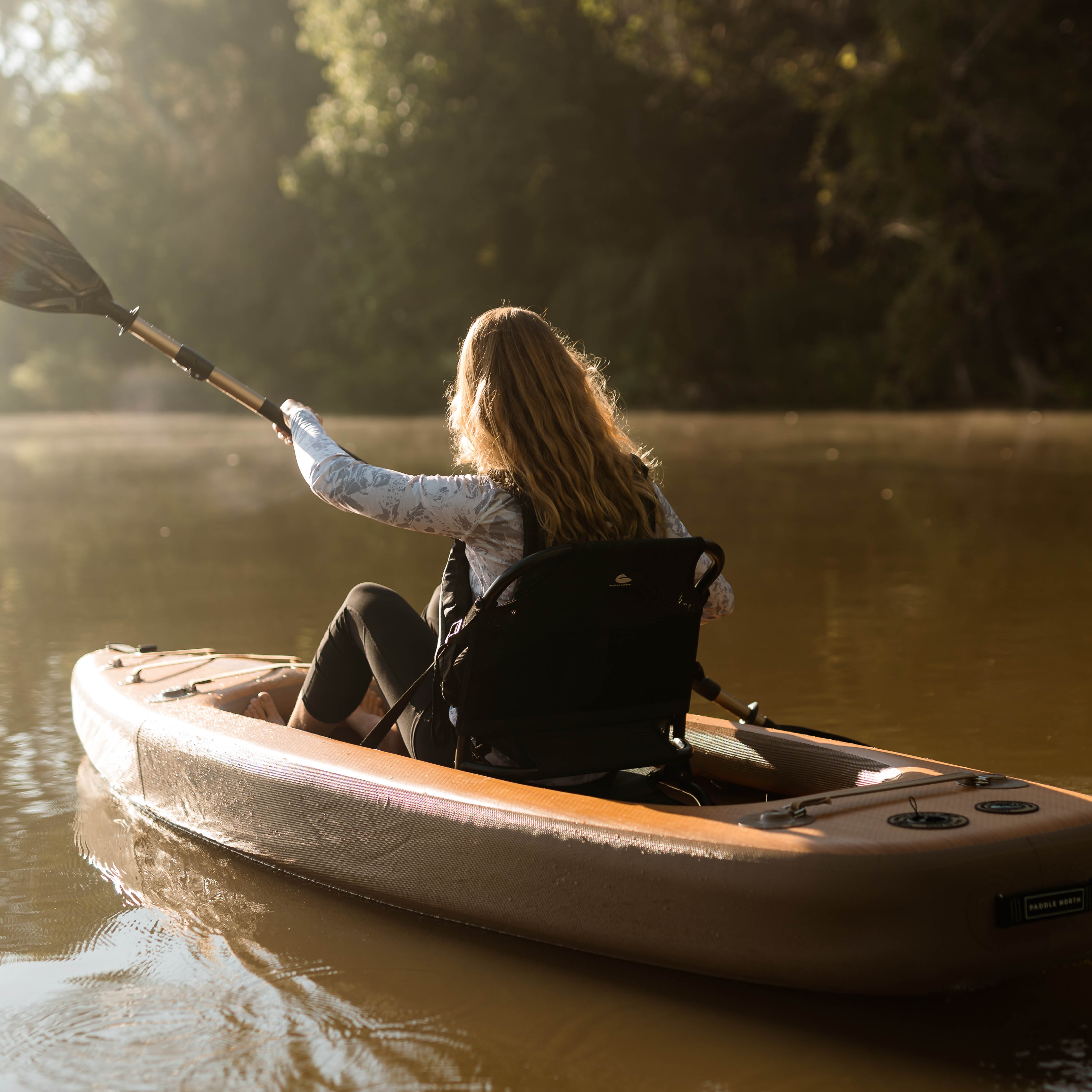 Person kayaking on a calm river with trees in the background