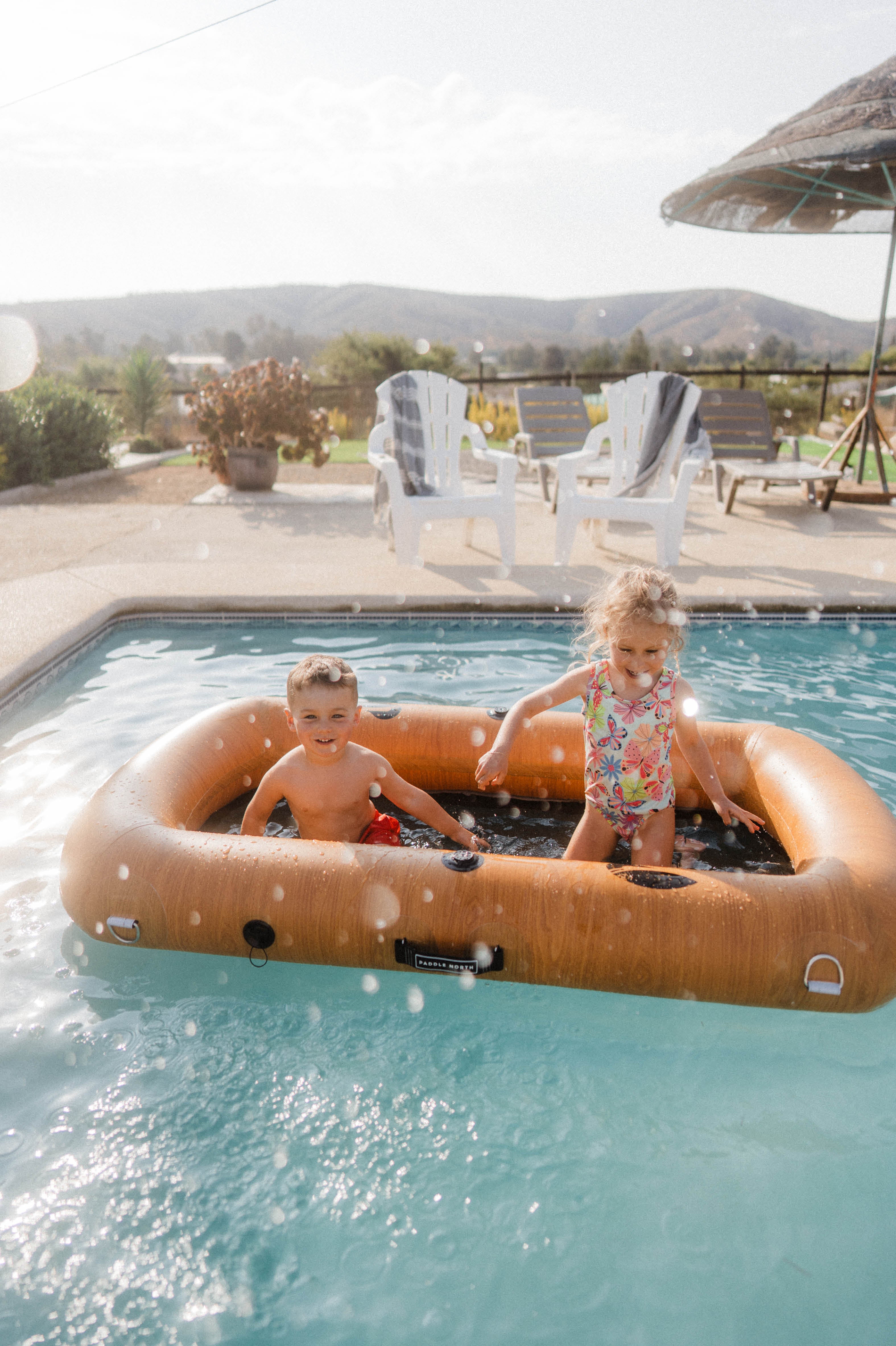 Kids playing on inflatable float in pool.