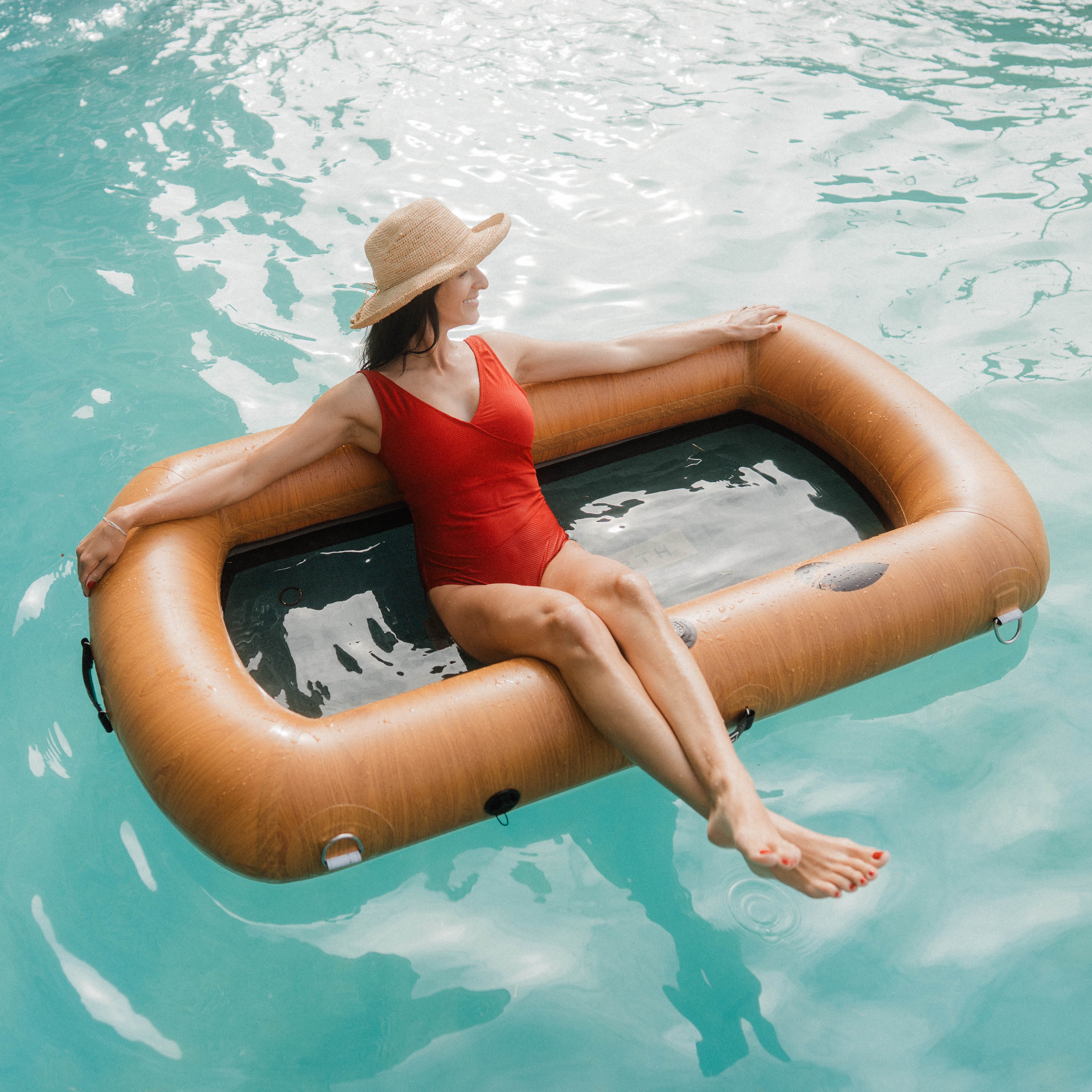 Woman in red swimsuit relaxing on inflatable float in pool.