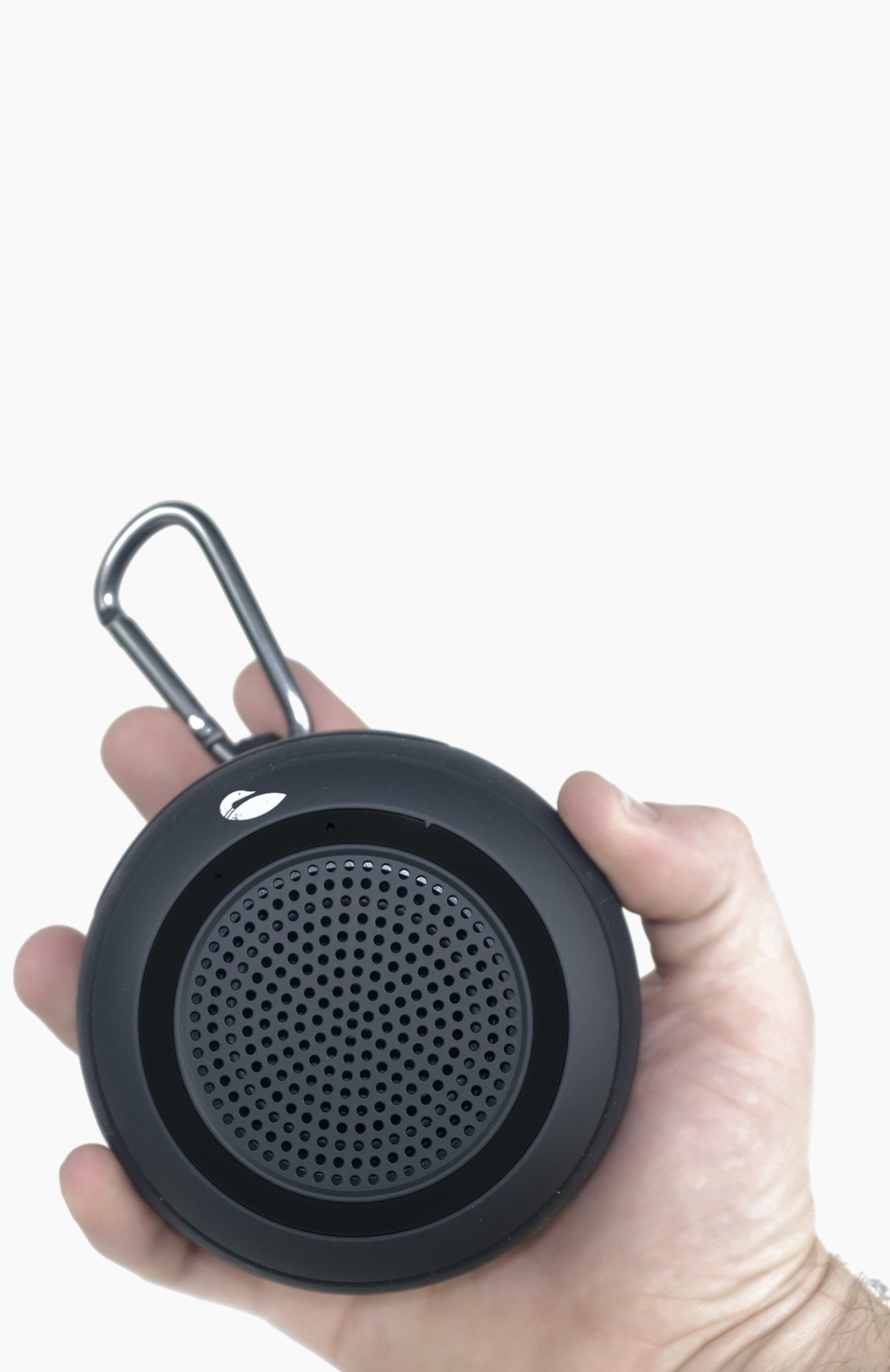 Someone holding a black circular speaker in their hand.