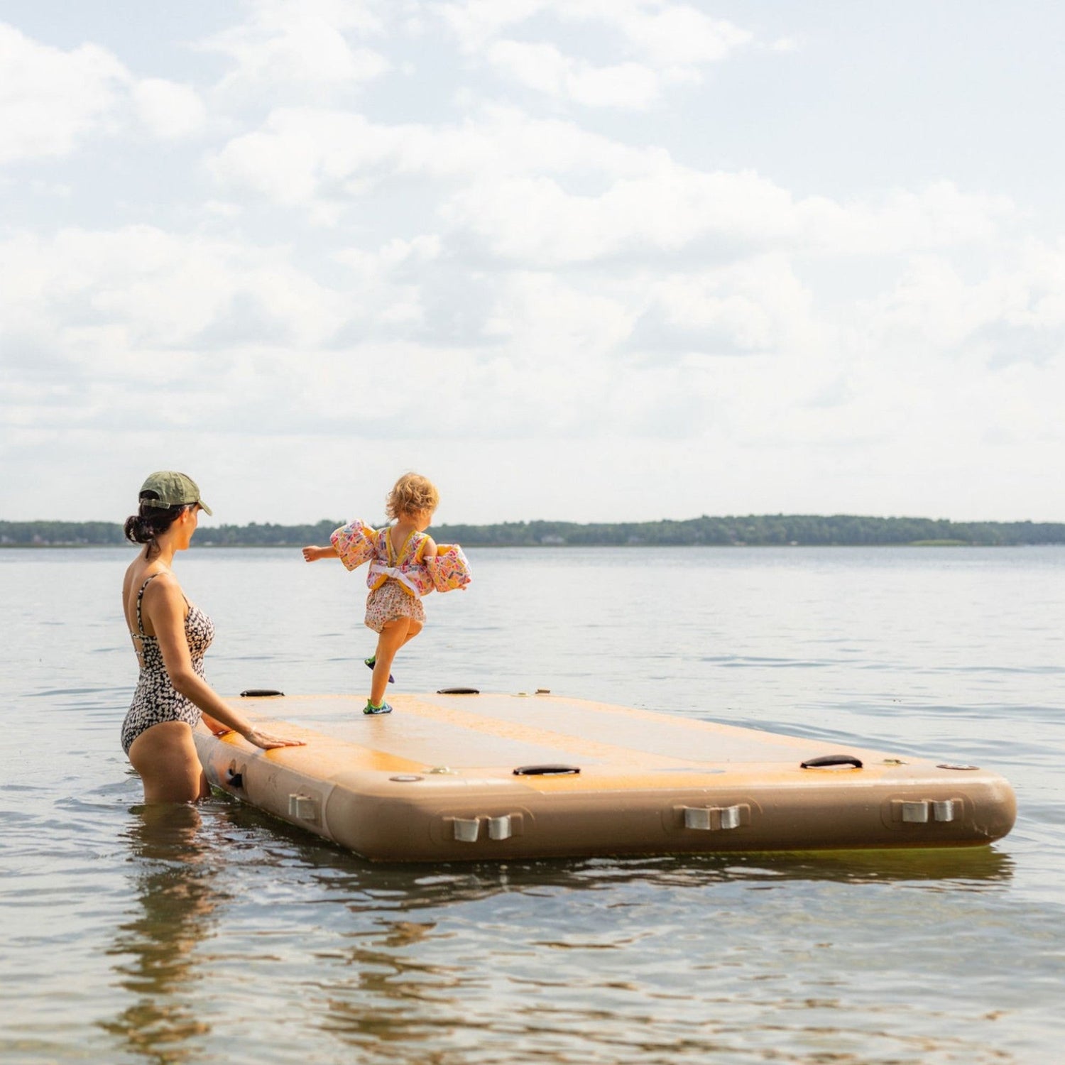 mother watching daughter jump off inflatable raft
