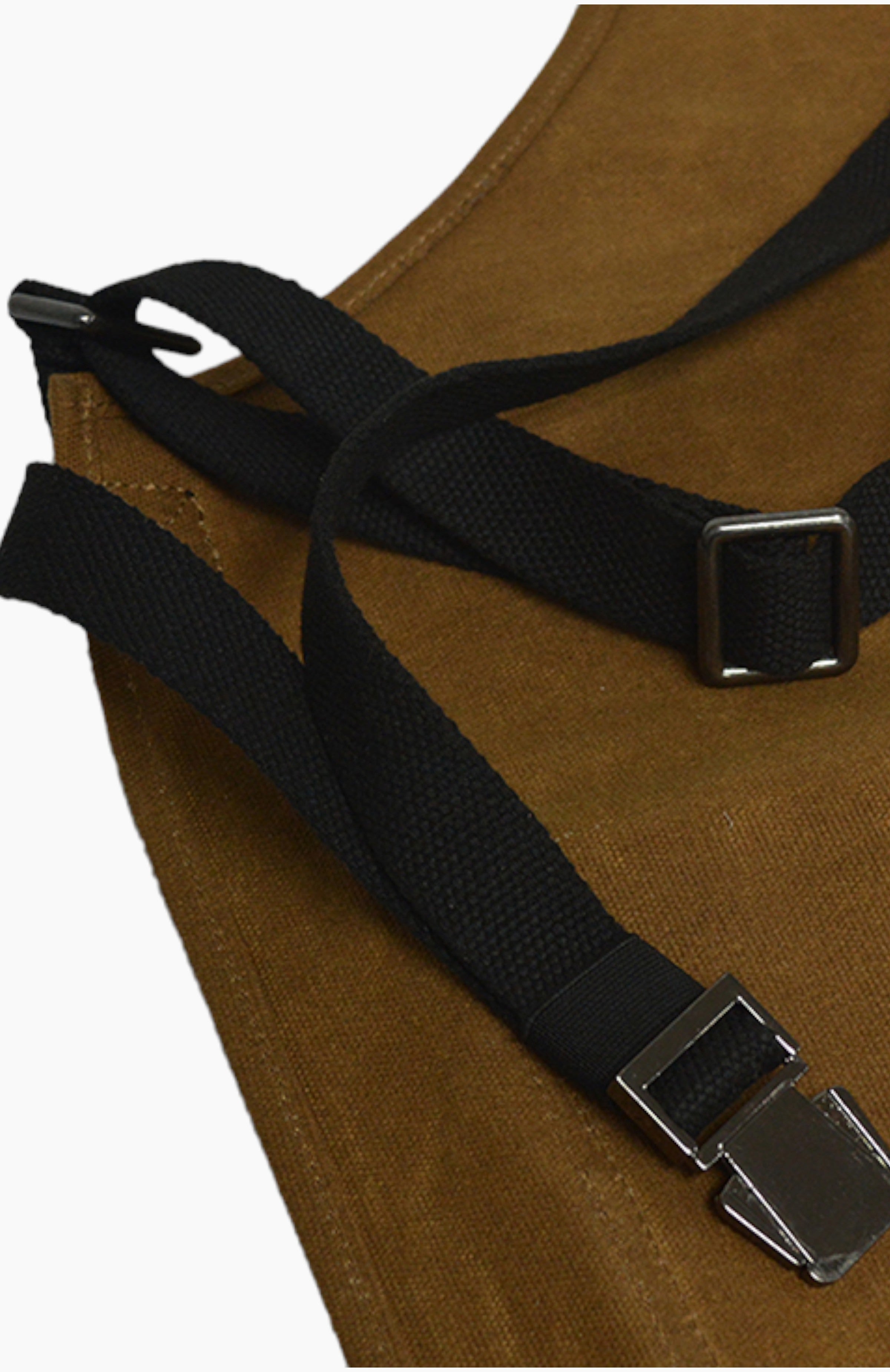 Close up of black straps and metal clasps on a brown leather apron.