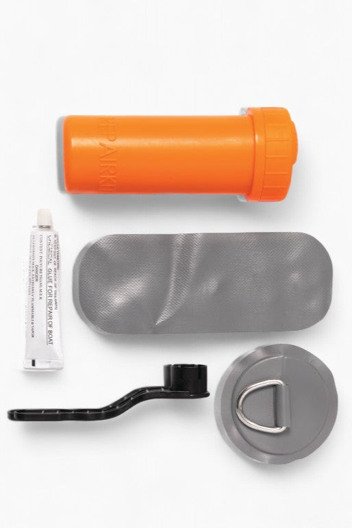 Contents of a repair kit including patches, a wrench, glue, and the orange container.