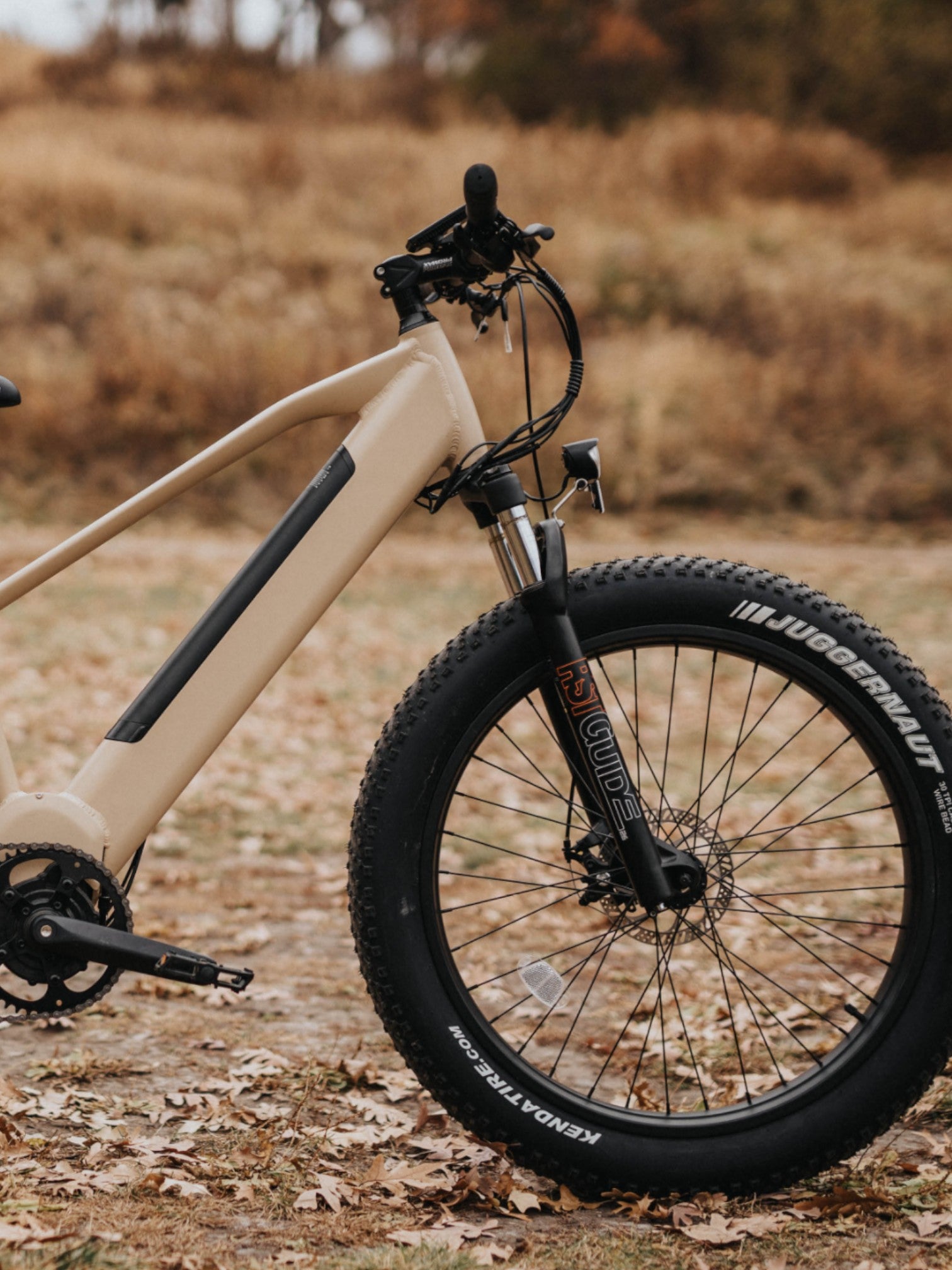 Front half of a tan electric bike with black handlebars and wheels.