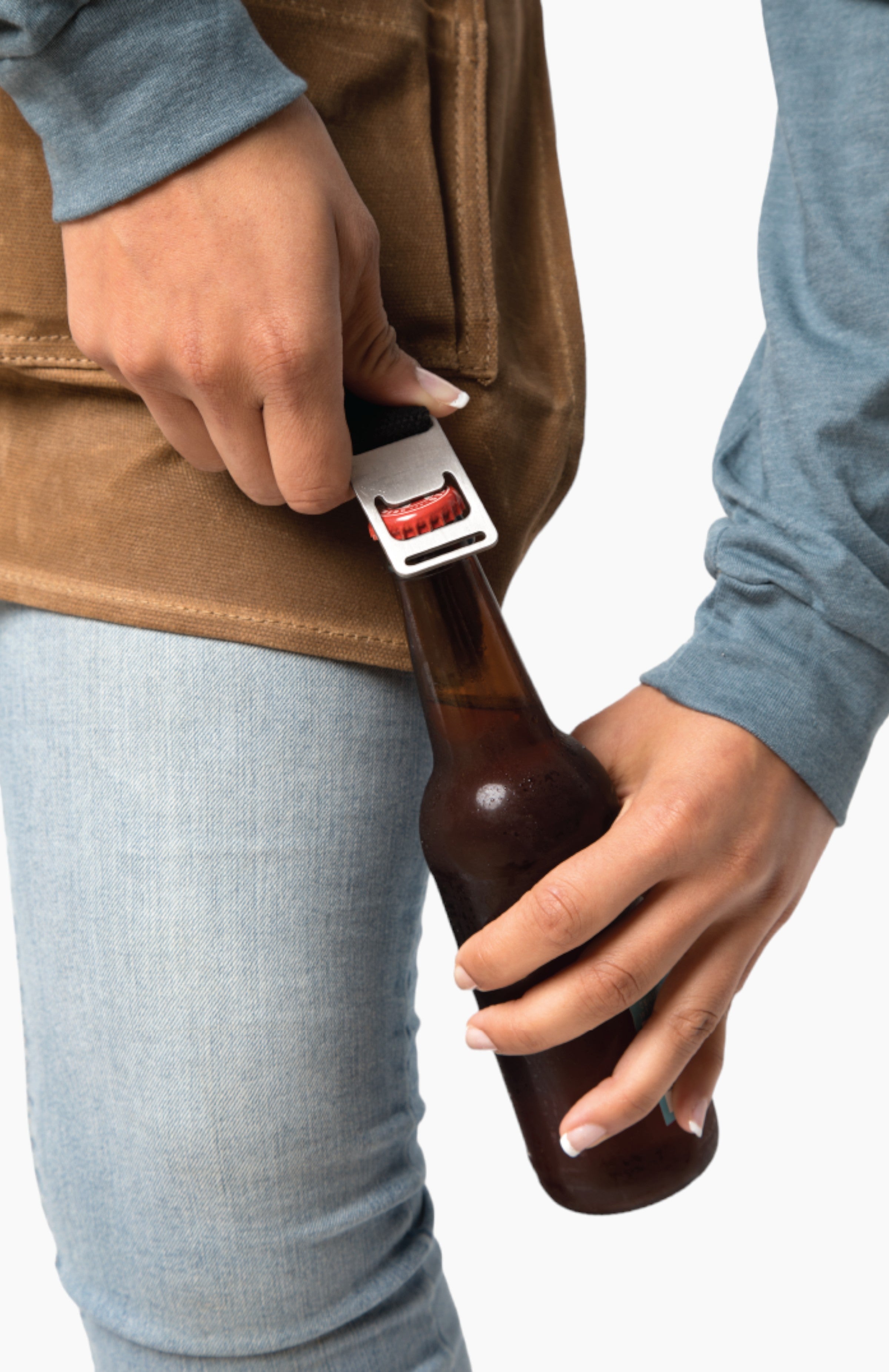 A person opening a bottle with a bottle opener that is attached to the apron.