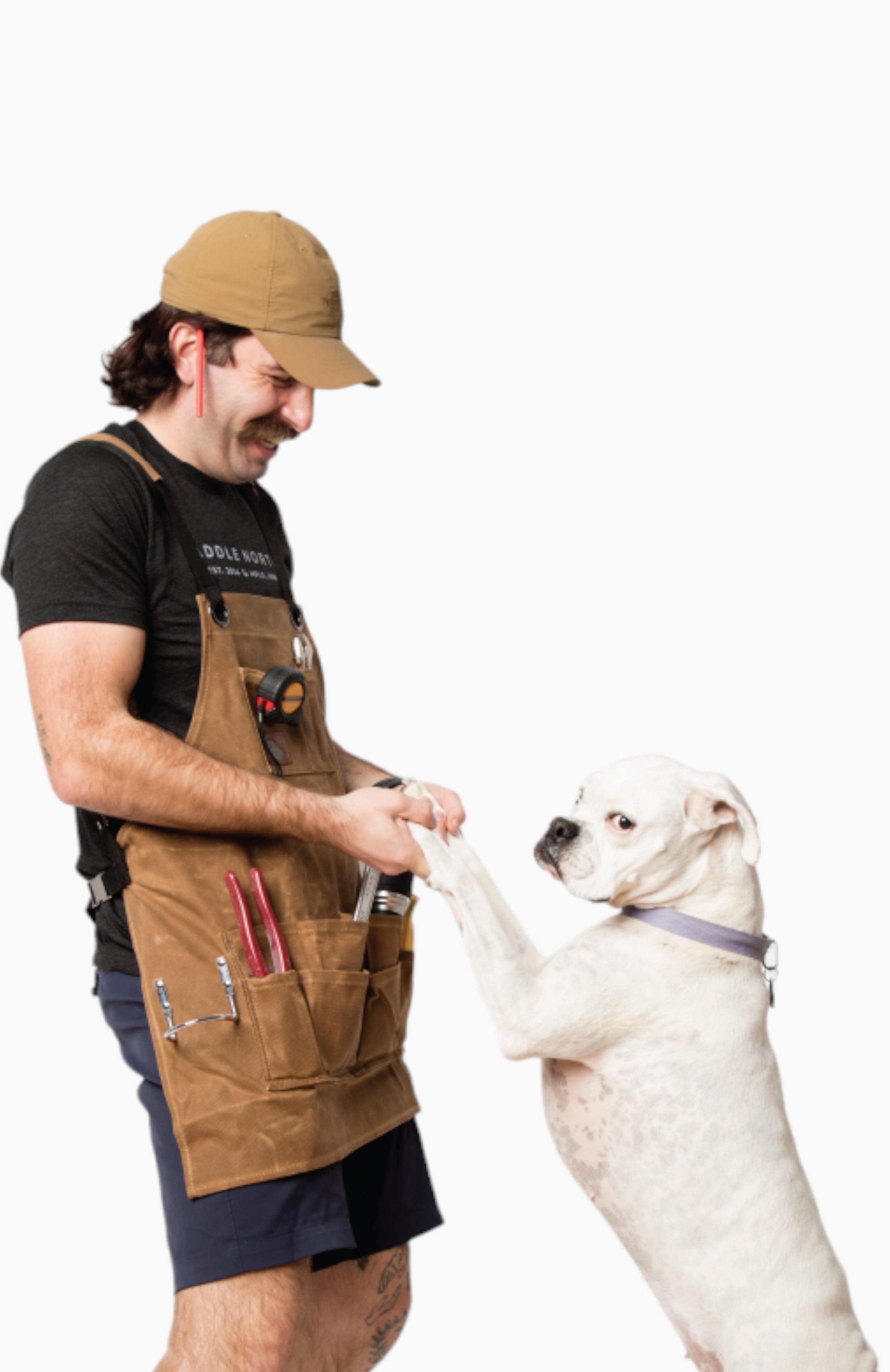 Man wearing a brown leather apron playing with a dog.