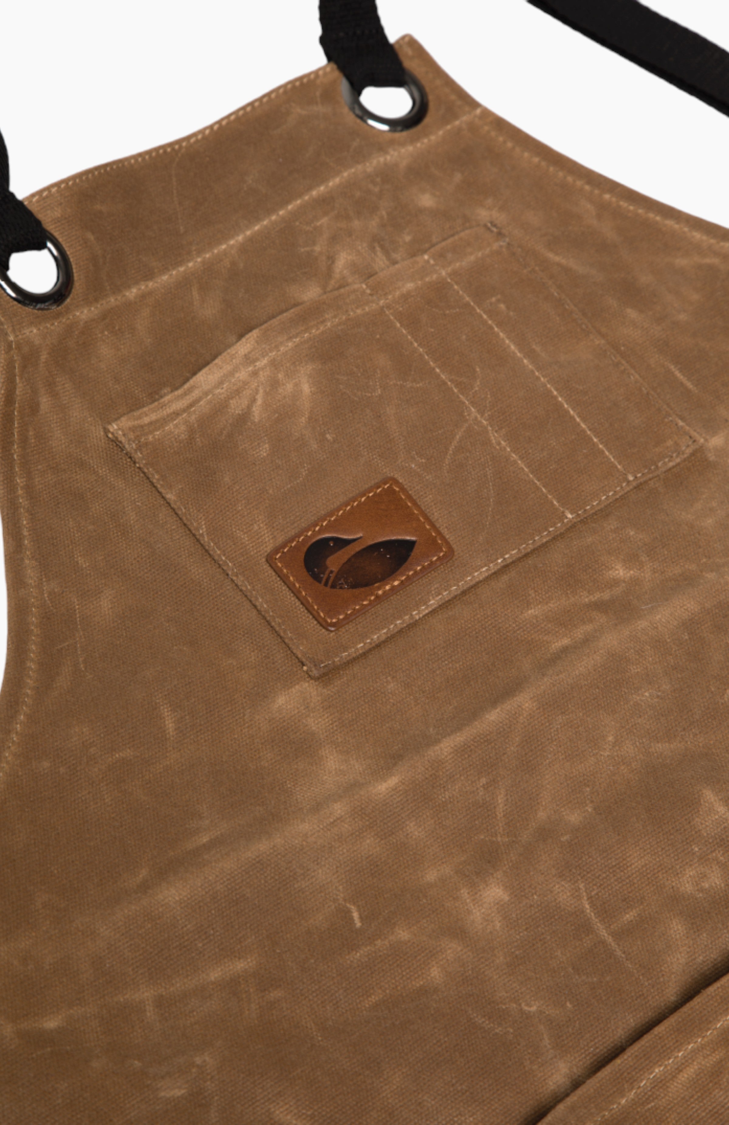 Close up of the brown leather apron chest pocket with a leather paddle north logo badge.