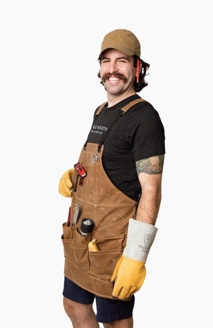 Man wearing brown leather apron with tools in the pockets and rubber gloves.