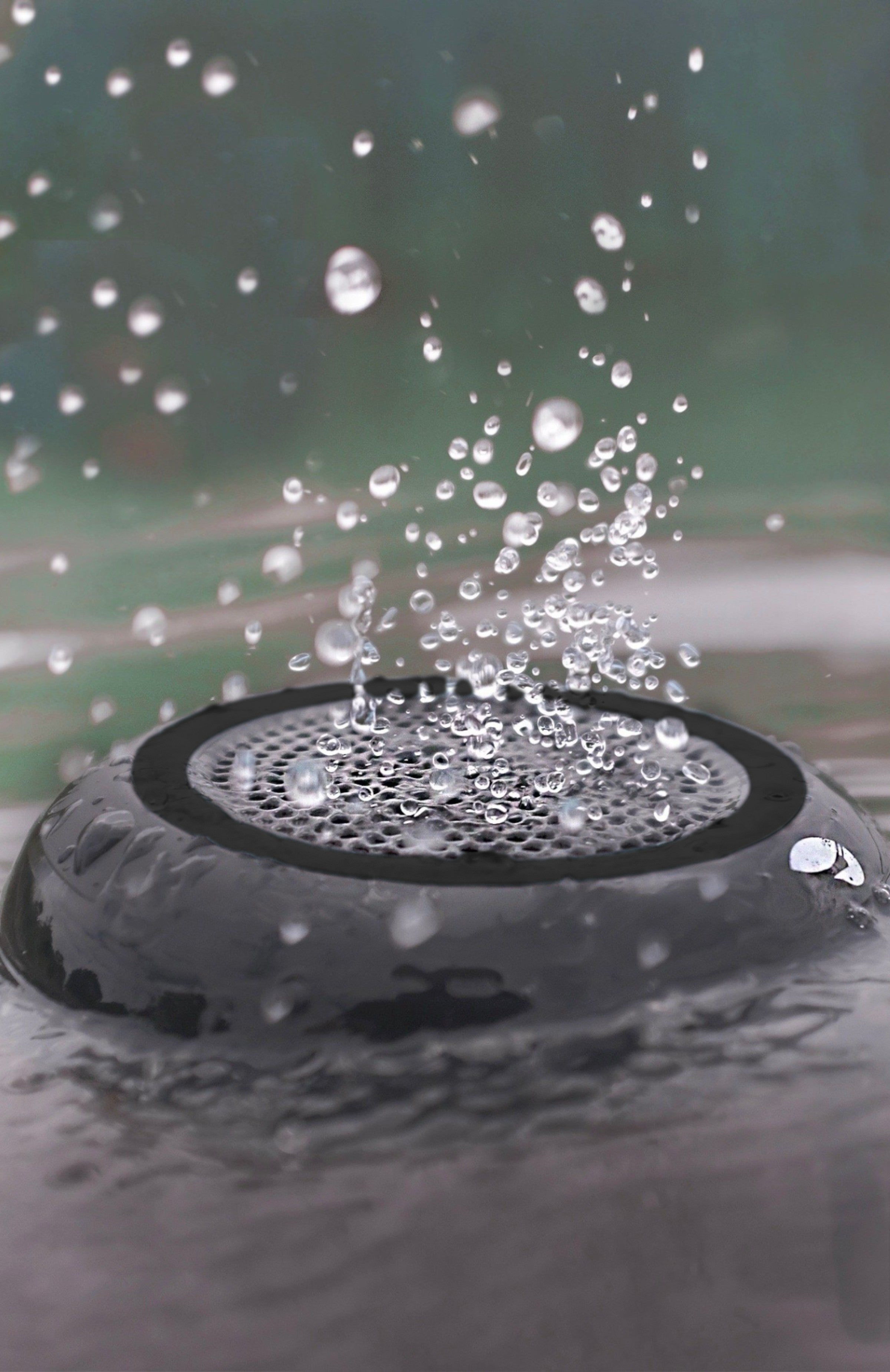 Speaker submerged in water with water drops bouncing off it.