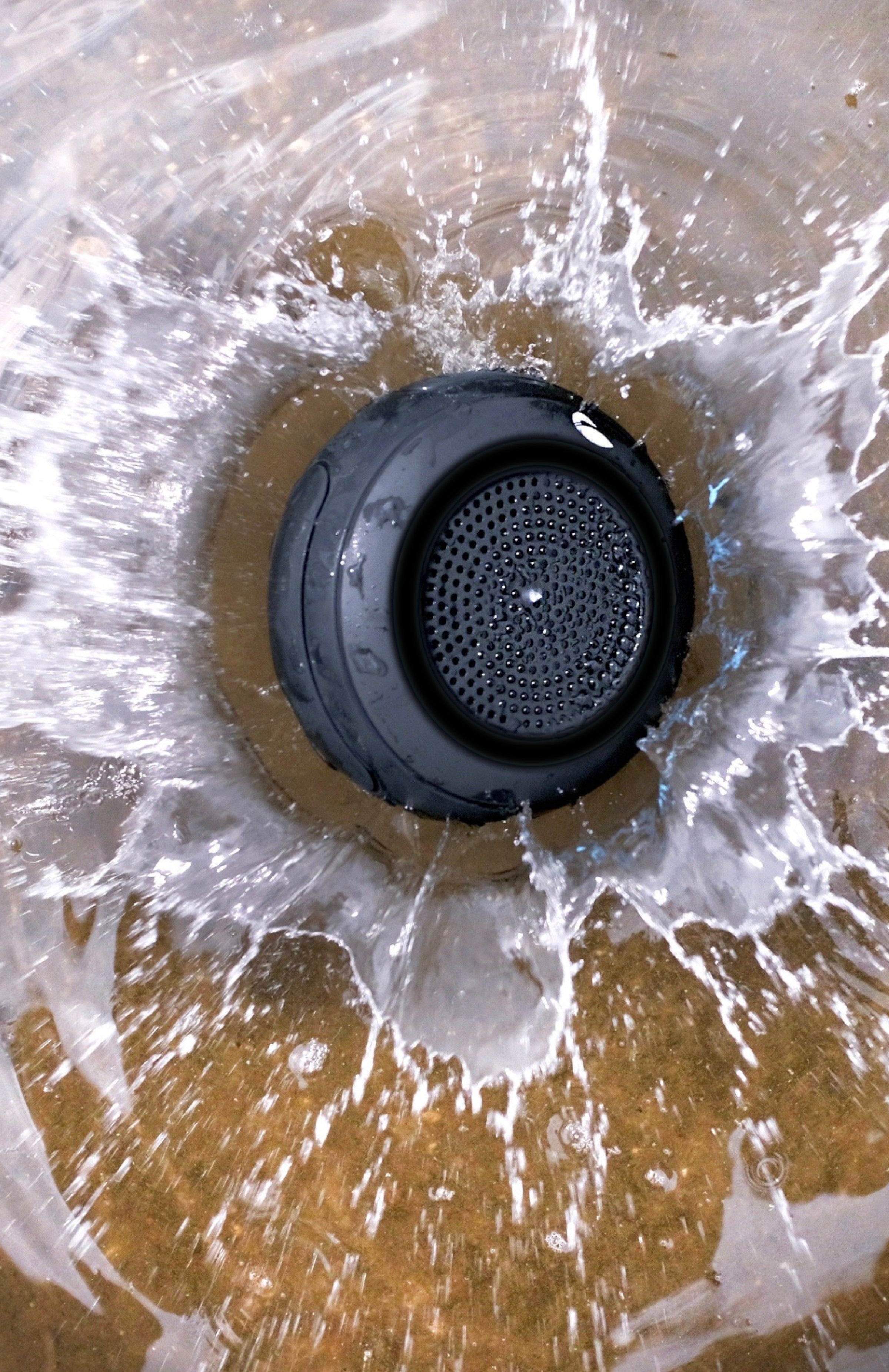 Black circular speaker falling into water making a splash.