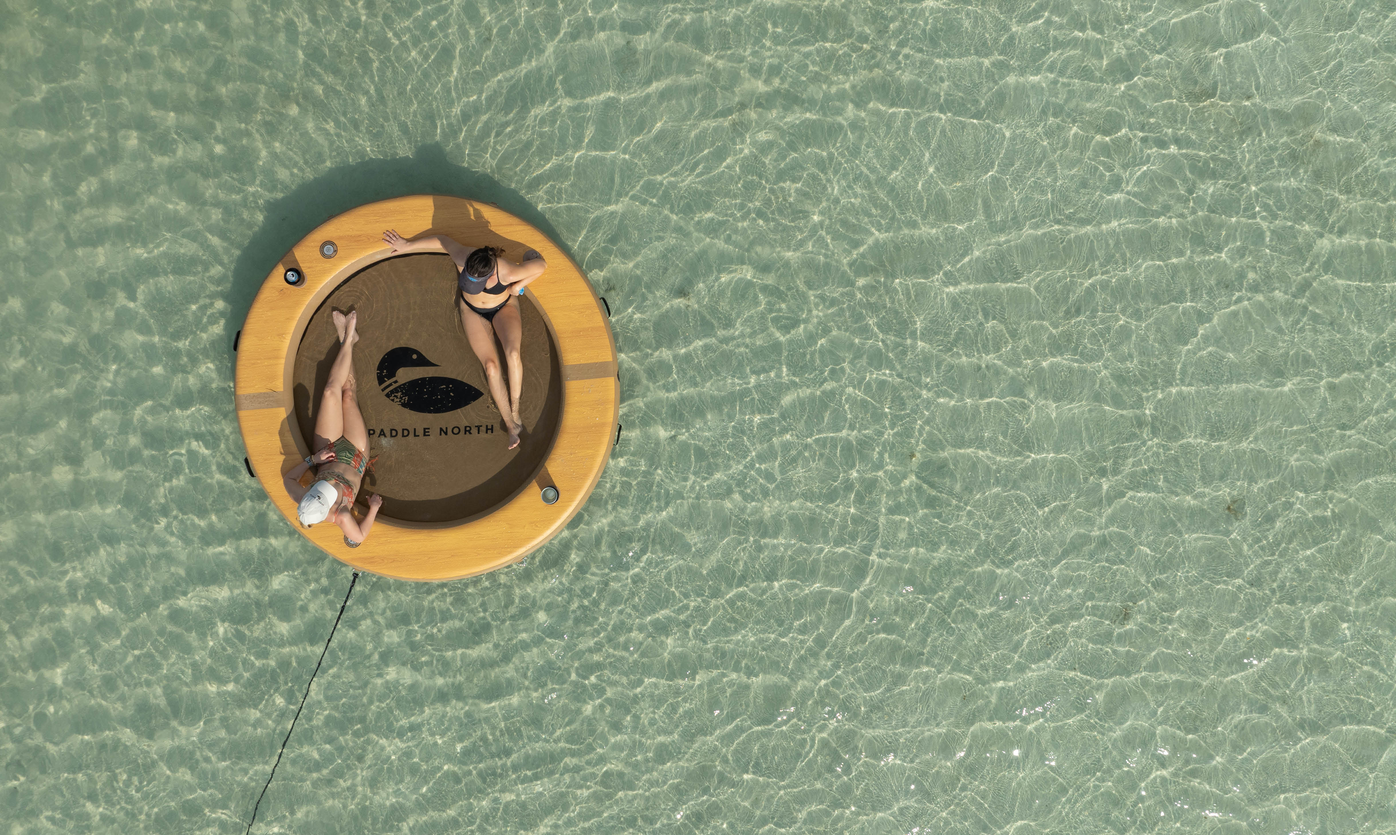 Two people in a circular inflatable float in clear water